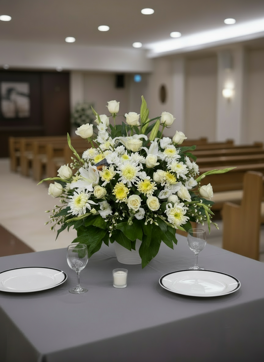 Floral arrangement on a table with plates and glasses in a church setting