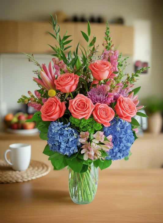 Colorful bouquet of flowers in a vase on a wooden table with a blurred kitchen background